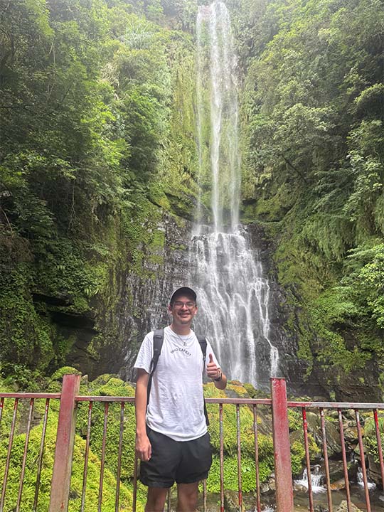 student standing in front of waterfall