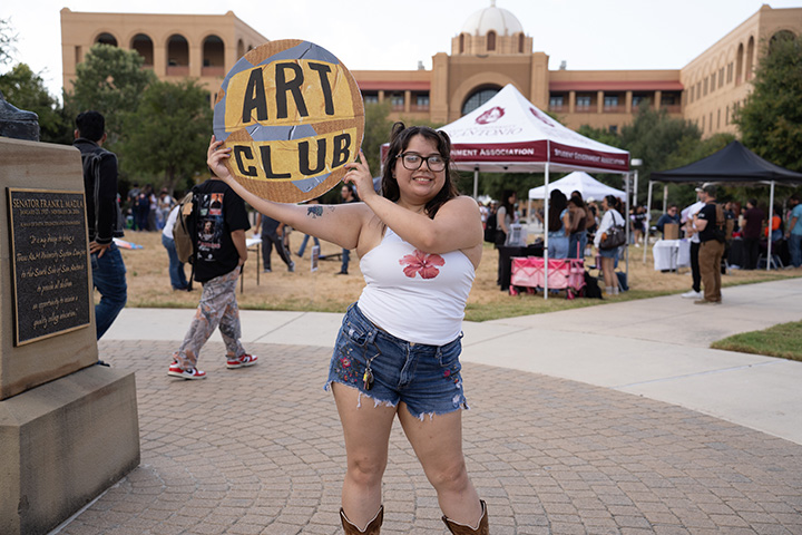Student Holding Art Club Sign
